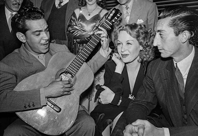 Archivo:1945. Manolete sonríe a la cámara en un escorzo imposible con una copa en la mano y Cantinflas ameniza a la compañía femenina, la actriz y espía alemana Hilda Kreuger (1945).jpg